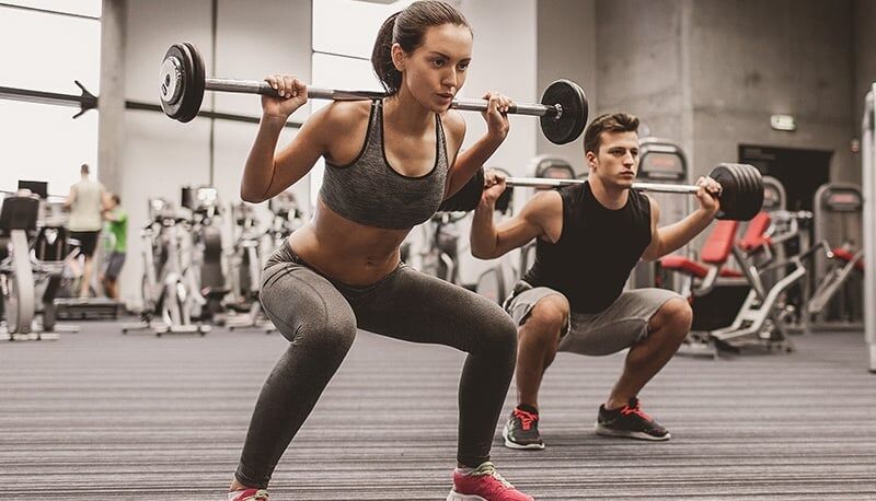Two people training with barbells in a gym