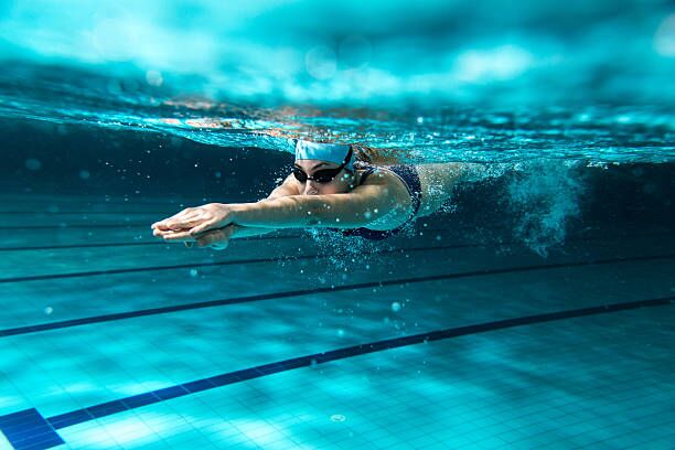 A swimmer doing front crawl in a lane pool, seen from underwater